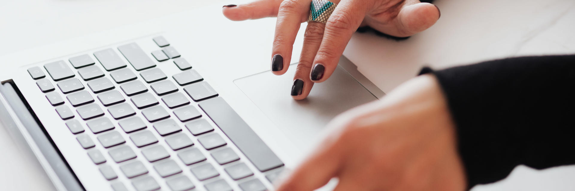 A woman using a laptop, cropped to just show he hands on the keyboard